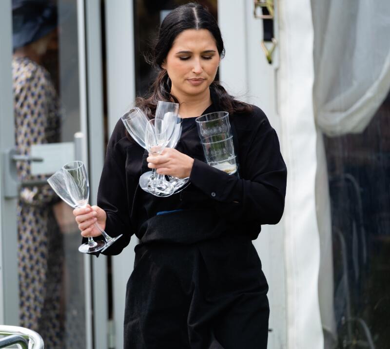 A member of waiting staff at Worcester Racecourse carries glasses
