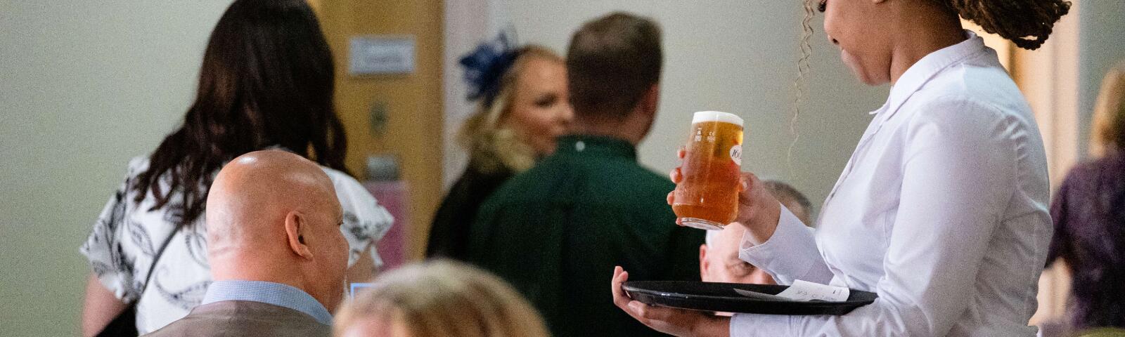 A member of waiting staff at Worcester Racecourse serves drinks to guests
