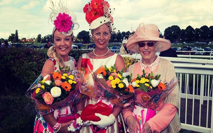 Three ladies posing with a bouquet of flowers each