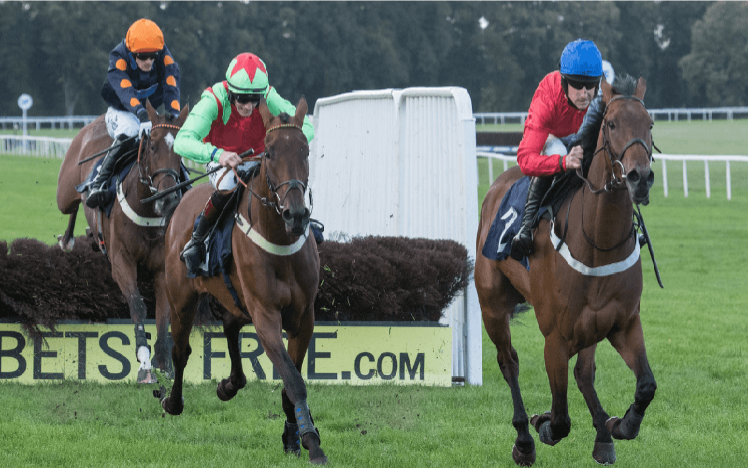 An image as three runners at Worcester Racecourse run towards the camera after clearing a fence.