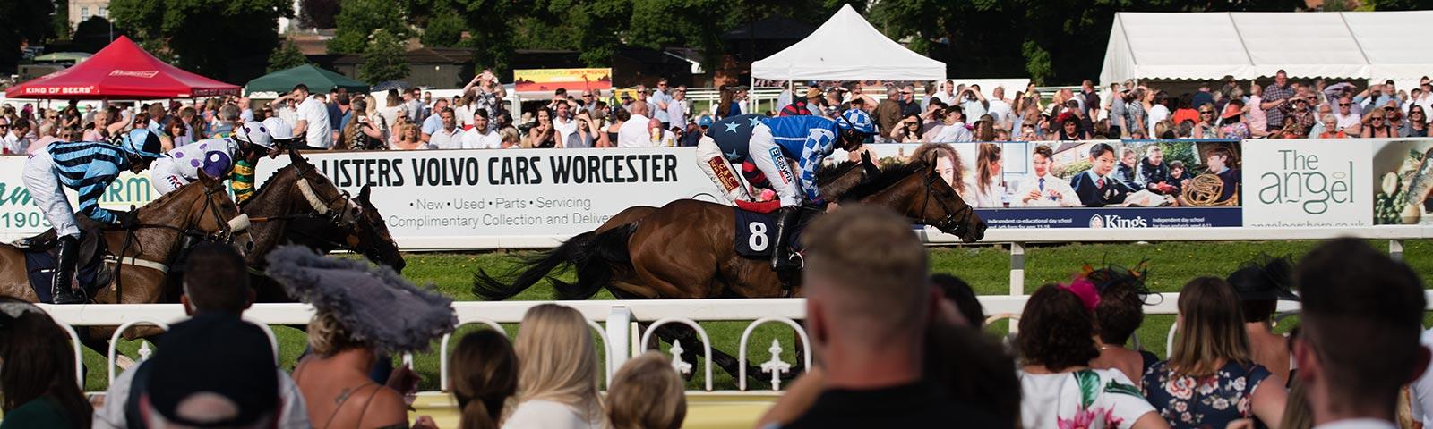 Crowds watching racing action at Worcester Racecourse.