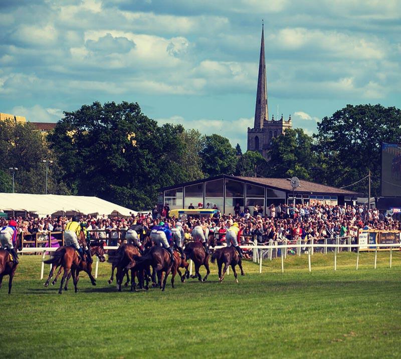 Group of jockeys racing at Worcester Racecourse.