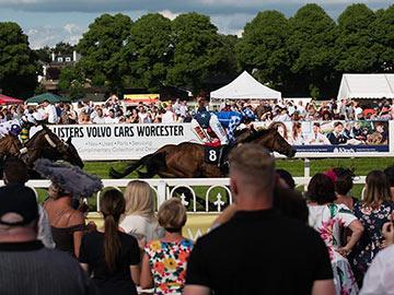 Crowds watching racing action at Worcester Racecourse.