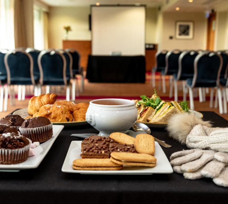 meeting room, table with muffins, biscuits, soup, sandwiches, pastries and a hat and scarf 