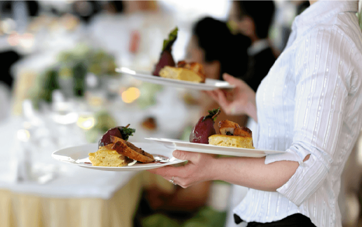 A member of waiting staff delivers starters