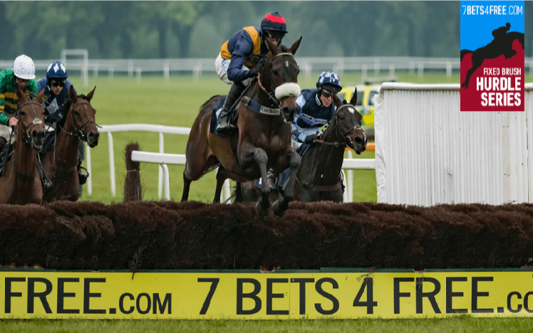 An image of runners in a horse race as they jump a fence