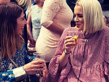 Two women at the races enjoying drinks.