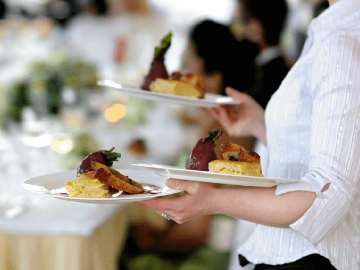 A member of waiting staff serves dessert.