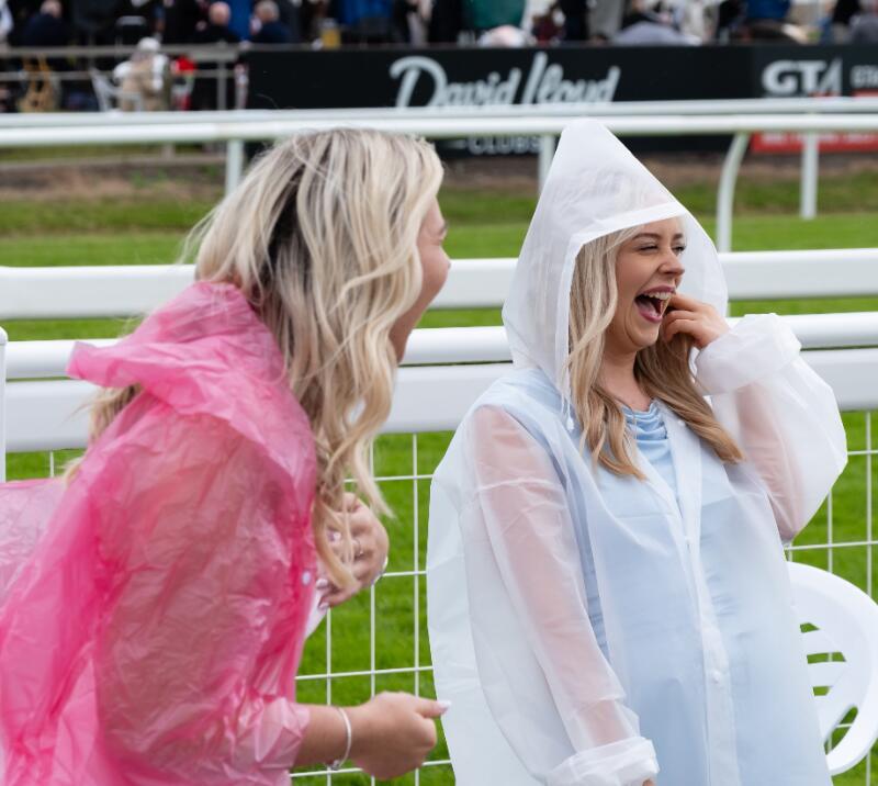Two girls in rain ponchos laughing at Worcester Racecourse